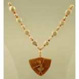 A PEACH JASPER CARVED PENDANT decorated with a ballerina, with coral, cultured pearls and mabe pearl