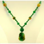 A HONEY JADE CARVED PENDANT, mounted on a jade bead necklace of alternate large and small beads,