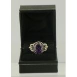 A RHODIUM FINISHED SILVER COLOURED METAL MOUNTED DRESS RING set with amethyst and simulated