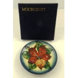 A MOORCROFT EARTHENWARE PIN DISH having stylised leaf "Tiger Lily" in red and green, with blue