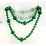 AN APPLE GREEN JADE LONG NECKLACE of large facetted beads interspersed by three smooth round