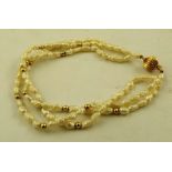 A 14K GOLD THREE STRAND BRACELET decorated with seed pearls