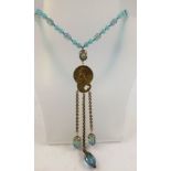 AN ART NOUVEAU SAUTOIR a blue bead necklace suspending a cast pendant with figure decoration and