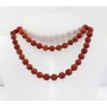 A CARVED CORAL BEAD NECKLACE with 9ct gold clasp (doubled measures 40cm)