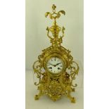 AN ORNATE FRENCH CAST BRASS CASED MANTEL CLOCK with mask decoration, white enamel dial with Roman