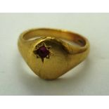 AN 18CT GOLD UNISEX SIGNET RING having oval un-engraved top set with a ruby