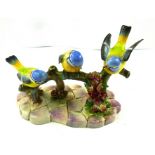 A MID 20TH CENTURY STAFFORDSHIRE MODEL GROUP OF THREE BLUE TITS on a flowering branch, decorated