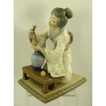 A LLADRO PORCELAIN FIGURE of a kneeling Japanese girl tending flowers, 20cm high