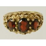 A 9CT GOLD GARNET SET DRESS RING having three graduated stones in a cast setting, size K