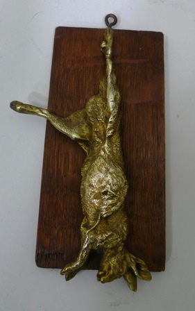 A LATE 19TH CENTURY ORMOLU CAST HANGING HARE mounted upon an oak board, 20cm