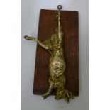 A LATE 19TH CENTURY ORMOLU CAST HANGING HARE mounted upon an oak board, 20cm