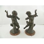 A PAIR OF 19TH CENTURY STYLE CAST AND PATINATED CHERUBS, each seated on a pedestal with polished