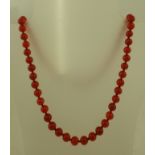 A RED GLASS BEAD NECKLACE with gold coloured metal clasp, 68cm long