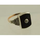 AN ART DECO INFLUENCED DIAMOND AND ONYX DRESS RING having central brilliant in an onyx surround,