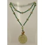 A NEPHRITE AND APPLE GREEN JADE BEAD NECKLACE with carved mammoth tooth monkey above a pendant drop,