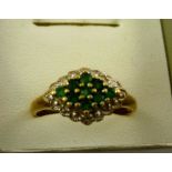 A MODERN GOLD COLOURED METAL DRESS RING having lozenge shaped head set with multiple emeralds, on