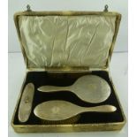 K** & L** A GEORGE V SILVER MOUNTED DRESSING TABLE SET, boxed, comprising a hand mirror, two brushes