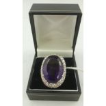 AN AMETHYST AND DIAMOND CLUSTER RING, having substantial oval mixed cut amethyst in claw setting,