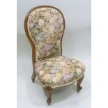 A LATE VICTORIAN MAHOGANY SHOW WOOD FRAMED NURSING CHAIR having floral upholstered seat and back, on