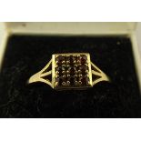 A 9CT GOLD DRESS RING having square head set with nine garnets, on a split wire shank, London