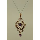 AN ART NOUVEAU DESIGN GOLD COLOURED METAL AND AMETHYST PENDANT, fashioned with two stones in claw