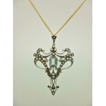 AN EDWARDIAN STYLE AQUAMARINE AND SEED PEARL FILIGREE PENDANT in silver and gold coloured metal