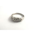 A DIAMOND SET WHITE GOLD COLOURED METAL DRESS RING, having five diamonds with tooled surround on a