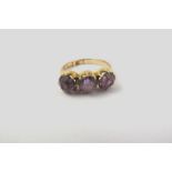 AN EDWARDIAN 18CT GOLD DRESS RING, set with three amethysts, size N 1/2