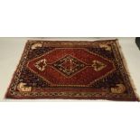 A QASHQAI RUG having deep red ground with central lozenge with spear head ends to the corners and