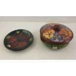 A MOORCROFT EARTHENWARE PIN DISH, with piped anemone decoration on blue ground, 12cm diameter, and a