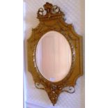 A REGENCY DESIGN GILT FRAMED WALL MIRROR, with scallop crest and floral swags, inset oval bevel