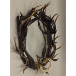 A TROPHY WALL MIRROR, the frame of entwined stag antlers, horns and tusks, to the base a metal mount