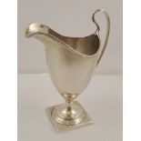 H*** A GEORGE III SILVER PEDESTAL CREAM JUG having reeded rim, swept handle and square base,