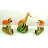 A SUITE OF THREE VICTORIAN STAFFORDSHIRE GREYHOUND MANTEL ORNAMENTS comprising; a pair 18 x 18cm and