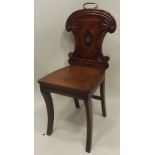 A REGENCY MAHOGANY HALL CHAIR having reeded and fan shaped scallop back with crested centre, solid