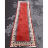 A PERSIAN RUNNER, plain crimson ground with decorative cream and blue border, 300cm x 80cm