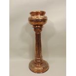 A NEWLYN STYLE COPPER JARDINIERE AND PEDESTAL, the pot with rolled rim and tooled leaf upper belly