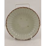 A CELADON GLAZED PORCELAIN SAUCER DISH with flutes and brown rim, 13.5cm diameter