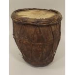 AN EARLY 20TH CENTURY ETHNIC HOLLOWED OUT WOODEN BASED TRIBAL DRUM with hide cover and stringing,