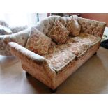 AN EDWARDIAN THREE-SEATER SOFA, having camel back, outswept upholstered arms, button back, three