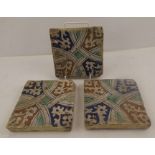 IN THE MANNER OF MORRIS & CO THREE TERRACOTTA TILES having entwined decoration in blue, green and