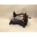 A VICTORIAN CAST IRON TABLE TOP SEWING MACHINE having serpent frame gilded with leaves