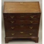 A LATE GEORGE III/EARLY 19TH CENTURY MAHOGANY BUREAU having crossbanded fall flap with pigeon hole