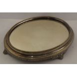 AN OVAL EPNS CAKE STAND, having mirror base, beaded surround, and raised on four cast scroll feet,