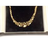 A FANCY 9CT GOLD COLLAR comprised of a graduated series of textured geometric forms and mounted with