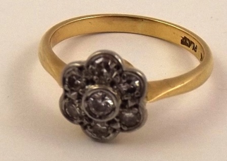 AN EARLY/MID 20TH CENTURY SEVEN STONE CLUSTER RING having floral head and plain wire shank in gold