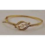 A VICTORIAN STYLE GOLD COLOURED METAL AND PEARL MOUNTED BANGLE, having triple pearl crossover