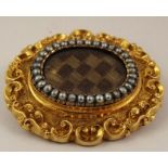 A VICTORIAN GOLD MOURNING BROOCH, the oval centre set with plaited hair bordered by seed pearls in a