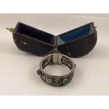A VICTORIAN SILVER BANGLE mounted with four green cabochon stones, ornamented with mistletoe and