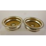 A PAIR OF 19TH CENTURY SILVER PLATED BOTTLE COASTERS with gadroon rims, crested to the centre of the